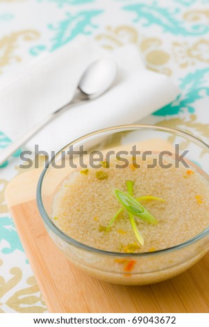 Bio quinoa soup in a bowl with wooden plate. Shallow depth of field.