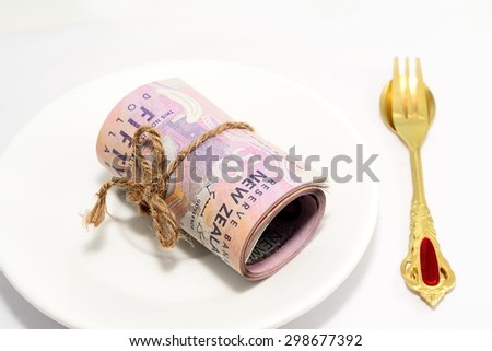 Roll of fifty Dollar New Zealand Tied in Burlap String Isolated on plate isolated with gold spoon and fork