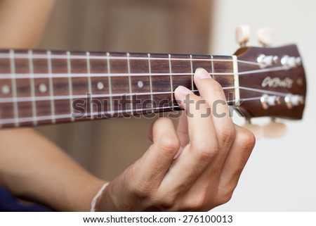 Close up playing ukulele , touch chord ,string instrument  , body part