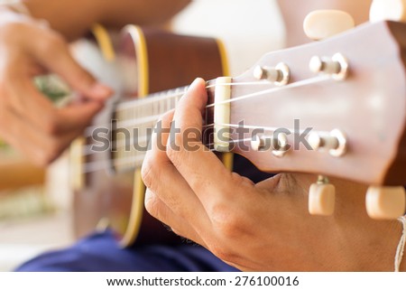 Close up playing ukulele , touch chord ,string instrument , body part