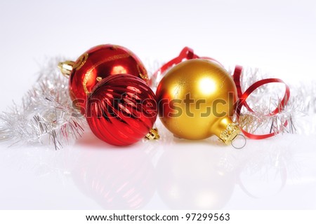 Elegant glowing red and golden-colored Christmas balls on a slightly textured reflective surface.