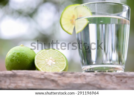 Lime and glass of lime juice on a wooden table.