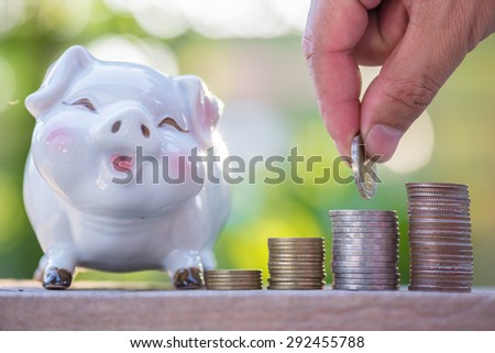 hand putting coin in increasing stack of money coins, saving money.