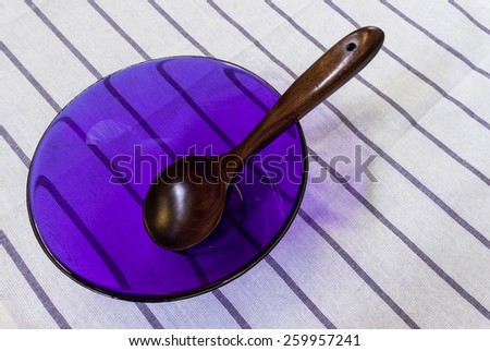 Wooden Spoon in Light Purple Cooking Glass Bowl Placed on White Table Background