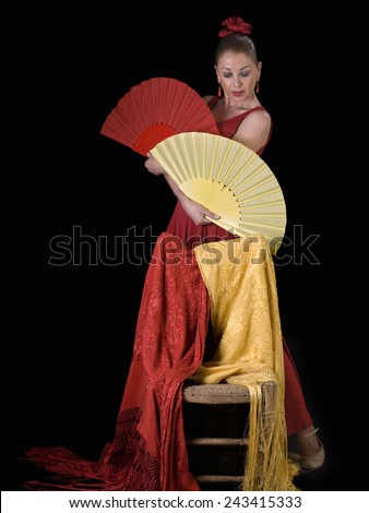 Women, dressed in flamenco, with two hand-held fans forming the colors of the Spanish flag
