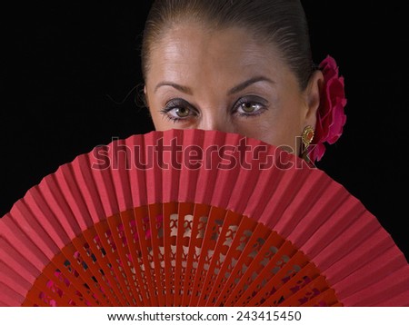 Closeup of a Flemish woman, from behind a hand fan, looking at the camera