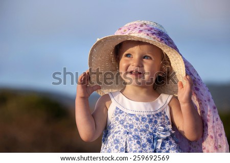 Girl of year and a half, smiling on having put on a lady\'s hat