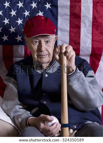 Old baseball player with bat and ball in front of an American flag