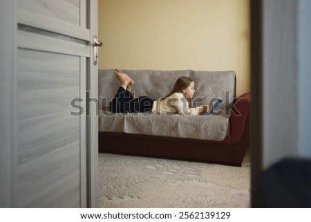 Similar – Image, Stock Photo Reading girl deeply absorbed in a book, stretching her feet from a colorful striped hammock