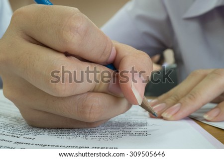 A hand of a girl writing on paper  using pencil