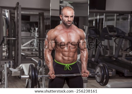 Handsome bodybuilder performing barbell biceps curls.