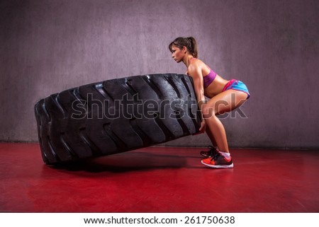 Fit female flipping tire at the gym.