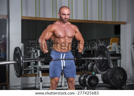 Bodybuilder performing exercises in the gym with bar and weights.