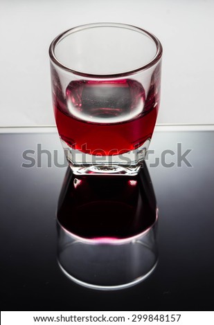A glass of red syrup put on reflect glass