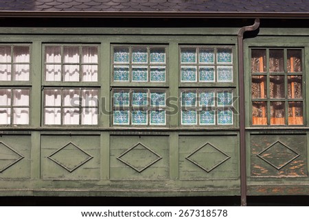 Old wooden green painted gallery windows with curtains in Spain.