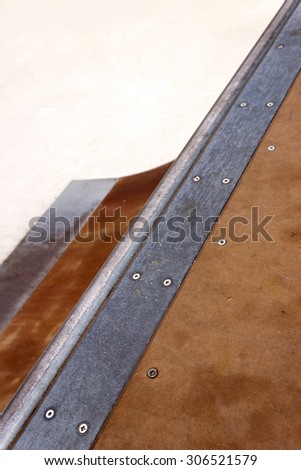 Detail of a wooden and metal quarter pipe ramp with rail in a skate park. Copy-space for placing text.