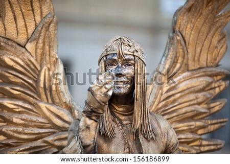BARCELONA, SPAIN - AUG 10: Human statue dressed as golden angel performing on La Rambla on August 10 2013 in Barcelona, Spain. La Rambla is most popular street in town always filled with tourists
