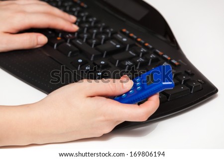Woman hands holding blue bank security token and typing on black keyboard.