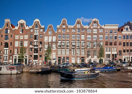 AMSTERDAM, NETHERLANDS - AUGUST 2, 2012: Boat cruising canal on a sunny day. Locals often ride in their boats on a sunny day.