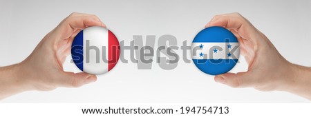 Man\'s hands holding styrofoam balls with French and Honduras flag against the white background.