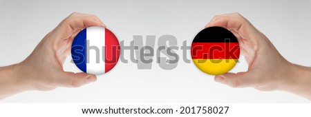 Man\'s hands holding styrofoam balls with French and German flag against the white background.