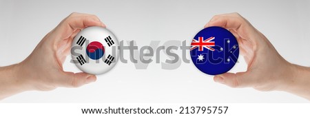 Man\'s hands holding styrofoam balls with South Korea and Australia flag against the white background.