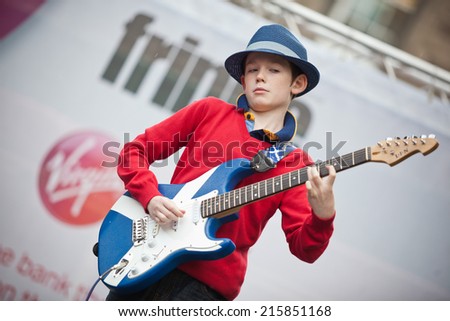 EDINBURGH, SCOTLAND: AUGUST 6, 2014: Little boy playing electric guitar painted as Scottish flag on Fringe festival. Fringe is the very popular and largest arts festival in the world.