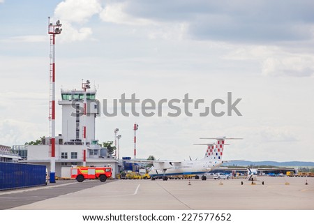 ZAGREB, CROATIA - APRIL 28, 2013: Airplane, bus and fire truck  parked on Pleso airport runway in front of air traffic control tower.