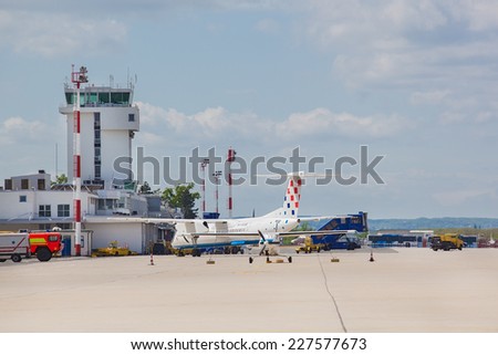 ZAGREB, CROATIA - APRIL 28, 2013: Airplane, bus and fire truck parked on Pleso airport runway in front of air traffic control tower.