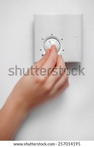 Closeup of woman hand turning on the analog thermostat. Post processed with radial blur zoom effect.