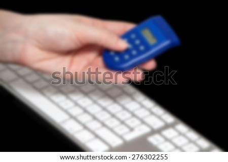 Woman hand holding bank security token in front of keyboard. Post processed with blur filter.