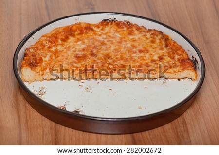 Half plate of homemade pizza on wooden table.