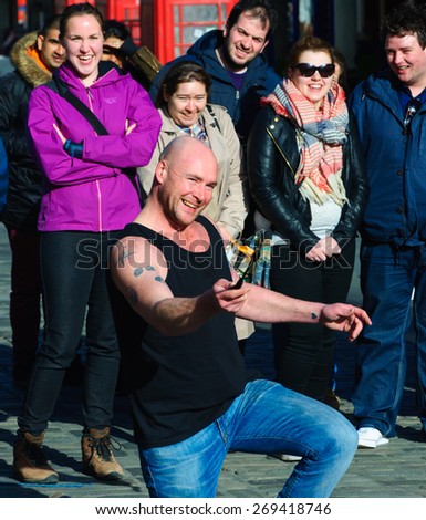 EDINBURGH, SCOTLAND -  11 APRIL, 2015: Street Artist performs with a lighted torch on the Royal Mile, Edinburgh