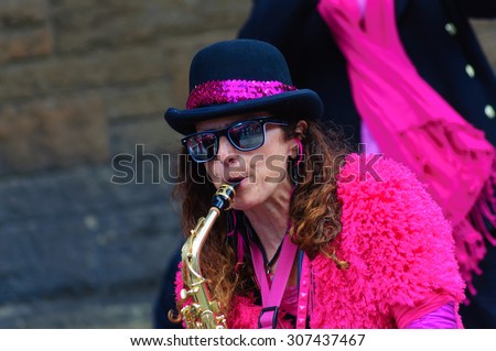 EDINBURGH, SCOTLAND - AUGUST 15, 2015: Female musician from The Ambling Band playing the saxophone at the Grassmarket during the Edinburgh International Fringe Festival