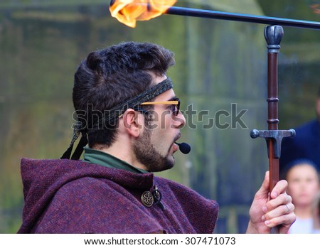 EDINBURGH, SCOTLAND - AUGUST 15, 2015: Male performer with sword and flaming torch on the Royal Mile during the Edinburgh International Fringe Festival