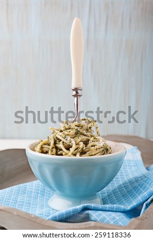 Spaghetti with kale pesto in blue bowl with fork