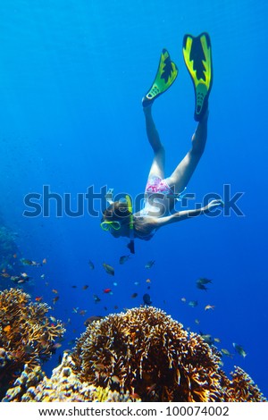 Young woman diving on a breath hold near a vivid coral reef