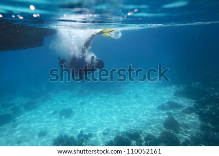 Underwater shoot of a diver doing back flip from a boat over coral reef
