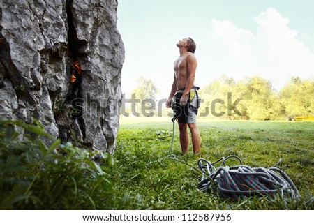 Young climber ready to conquer vertical wall with belay. Blue sky on the background