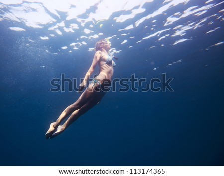 Young woman diving on a breath hold in a tropical sea