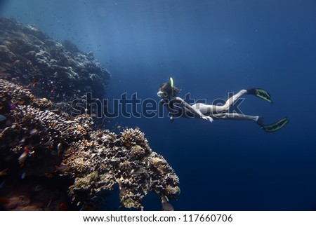Young woman diving on a breath hold by a coral reef