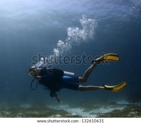 Scuba diver exploring tropical dive site and finning over bottom