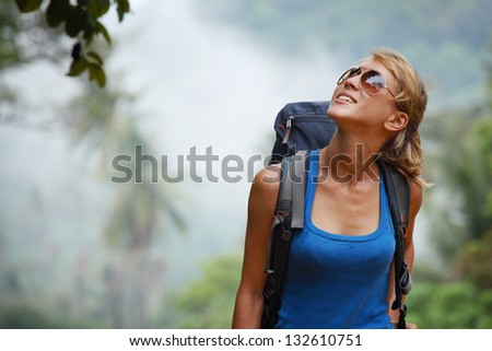 Young tourist with backpack walking in tropical forest
