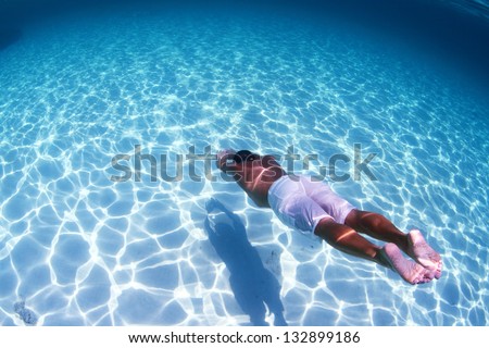Young man diving on a breath hold in a tropical sea over sandy bottom