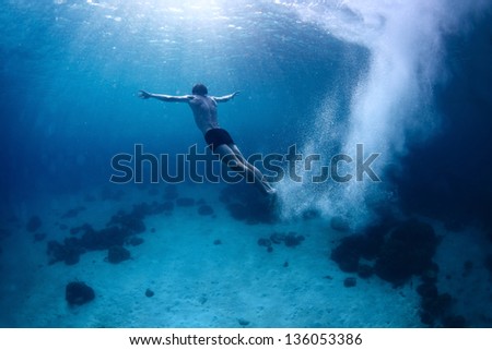 Underwater shoot of a young man jumping in a sea