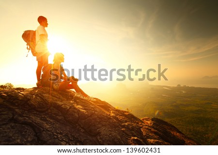 Hikers relaxing on top of a mountain and enjoying sunrise