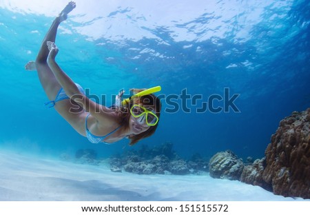 Young lady snorkeling and diving on a breath hold in a clear tropical sea