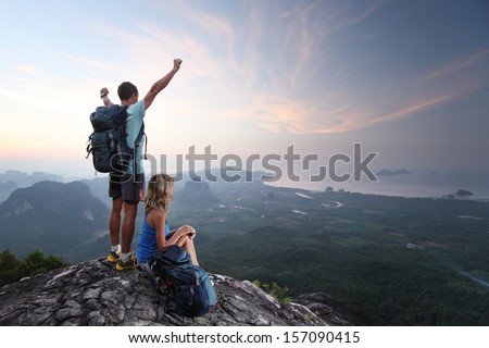 Hikers relaxing on top of a mountain and enjoying sunrise