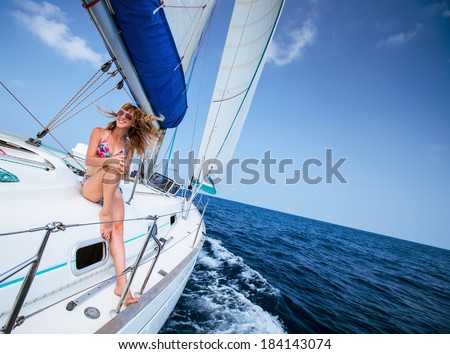 Young happy lady relaxing on the sail boat in the tropical sea at sunny day