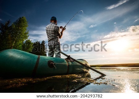 Mature man fishing from the boat at sunset